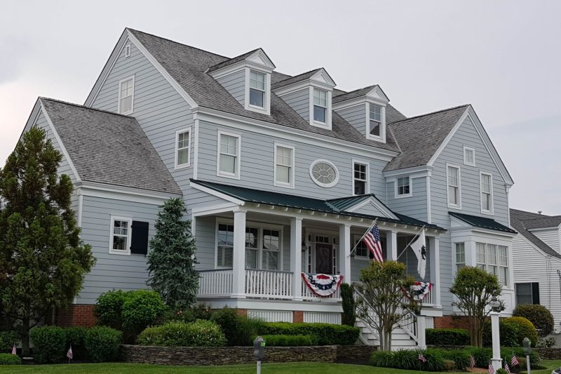 Elegant colonial-style house with manicured lawn and American flags in Cape May, NJ.
