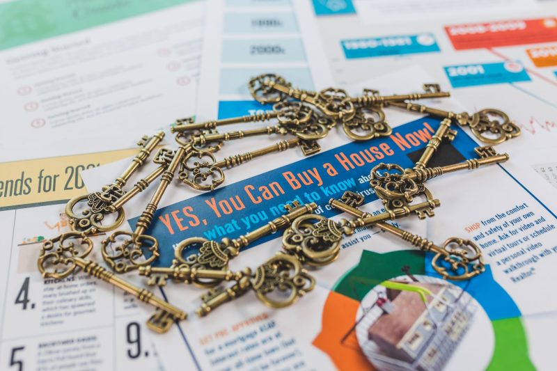 Vintage keys scattered on a real estate brochure highlighting house buying.